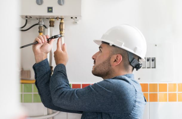  RS Andrews plumber repairing tankless water heater in Chesapeake, VA, home bathroom.
